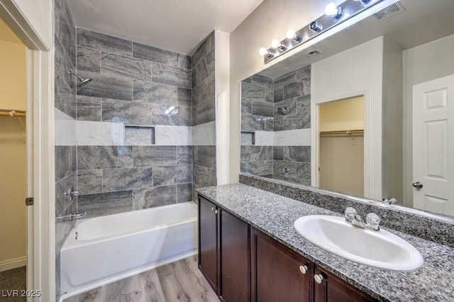 4516 Townwall St, Las Vegas, NV 89115 - bathroom featuring visible vents, wood finished floors, vanity, shower / bath combination, and a walk in closet