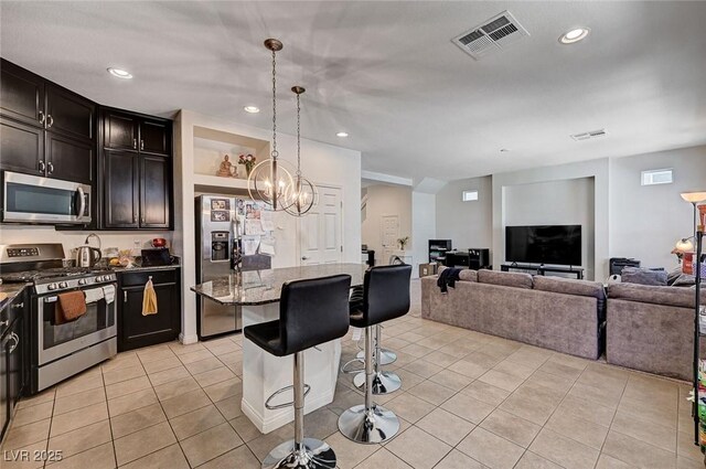 6516 Austin Hope Ave, Las Vegas, NV 89118 - kitchen with appliances with stainless steel finishes, a breakfast bar area, open floor plan, light tile patterned floors, and dark stone countertops