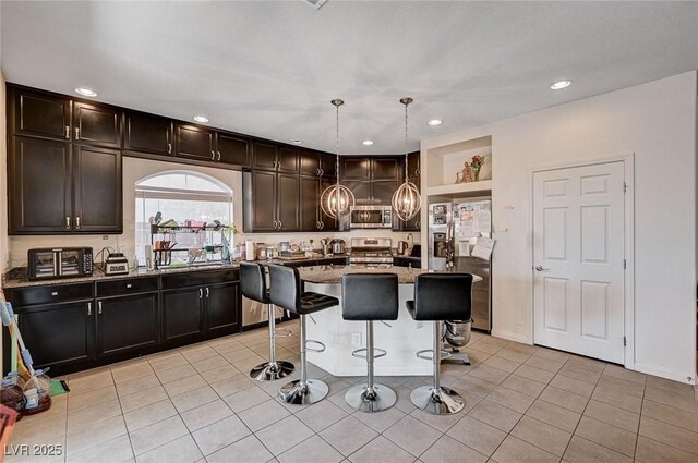 6516 Austin Hope Ave, Las Vegas, NV 89118 - kitchen with appliances with stainless steel finishes, a breakfast bar area, stone countertops, recessed lighting, and light tile patterned floors