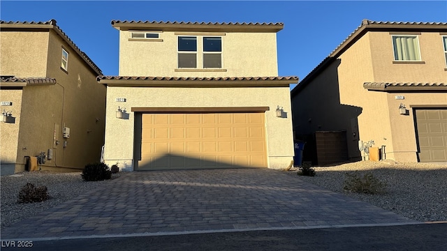 view of front of house with decorative driveway, a tiled roof, stucco siding, and a garage