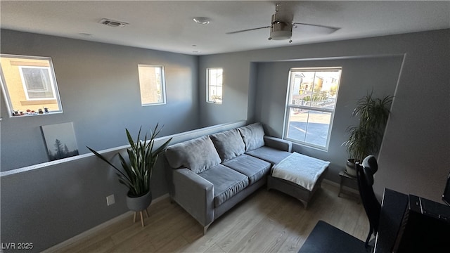 living area with baseboards, ceiling fan, visible vents, and light wood-type flooring