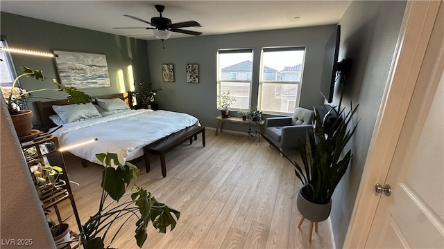 bedroom featuring a ceiling fan, baseboards, and light wood-style floors