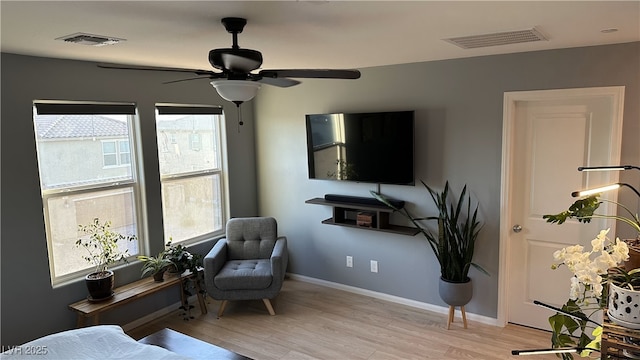 living area featuring light wood finished floors, baseboards, visible vents, and a ceiling fan