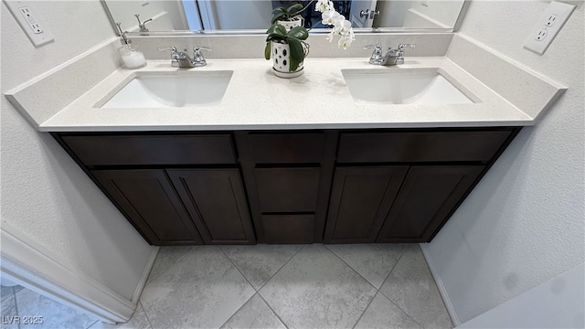full bathroom featuring double vanity, a textured wall, and a sink