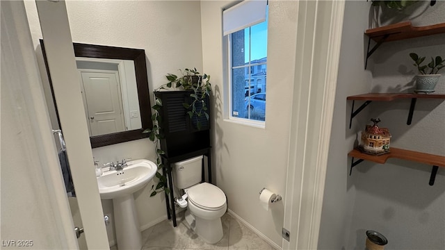 half bathroom with toilet, a sink, tile patterned flooring, and baseboards