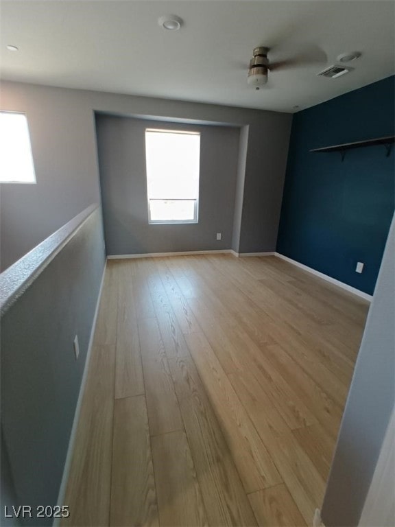 spare room featuring light wood finished floors, baseboards, and visible vents