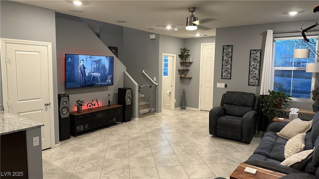 living room with stairs, light tile patterned floors, and a ceiling fan