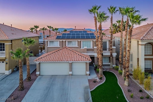 506 Staghorn Pass Ave, Las Vegas, NV 89183 - view of front of house with a tiled roof, stucco siding, driveway, solar panels, and a balcony