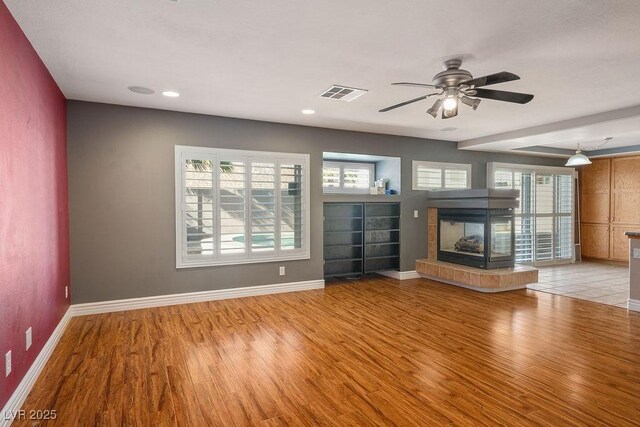 506 Staghorn Pass Ave, Las Vegas, NV 89183 - unfurnished living room featuring light wood finished floors, plenty of natural light, a tiled fireplace, and recessed lighting
