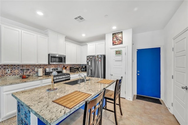7364 N Decatur Blvd Unit 4, Las Vegas, NV 89131 - kitchen featuring stainless steel appliances, a sink, a breakfast bar, decorative backsplash, and white cabinets