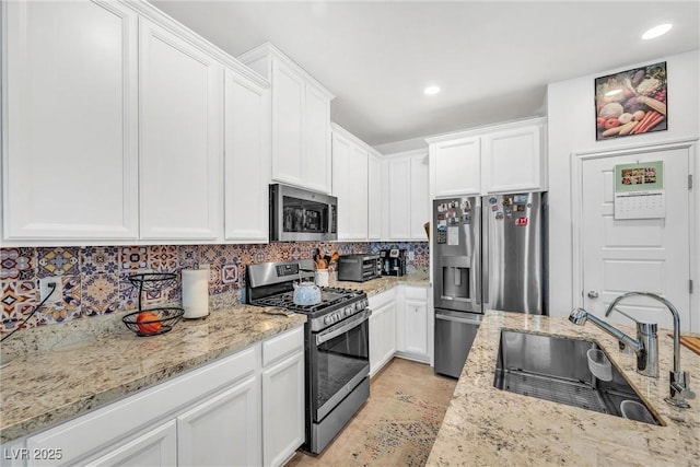 7364 N Decatur Blvd Unit 4, Las Vegas, NV 89131 - kitchen with stainless steel appliances, a sink, white cabinets, decorative backsplash, and light stone counters