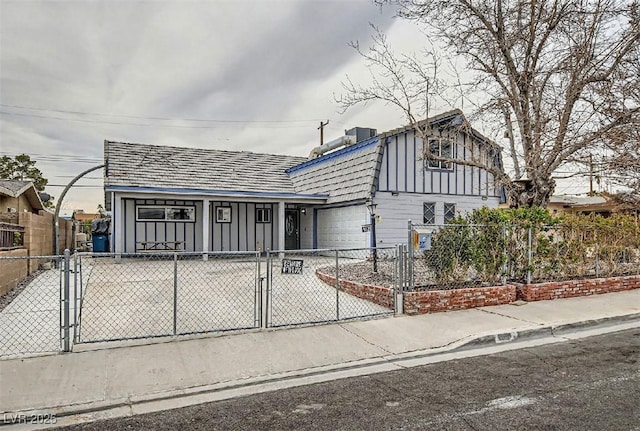 view of front of property with a gate, an attached garage, concrete driveway, a fenced front yard, and board and batten siding