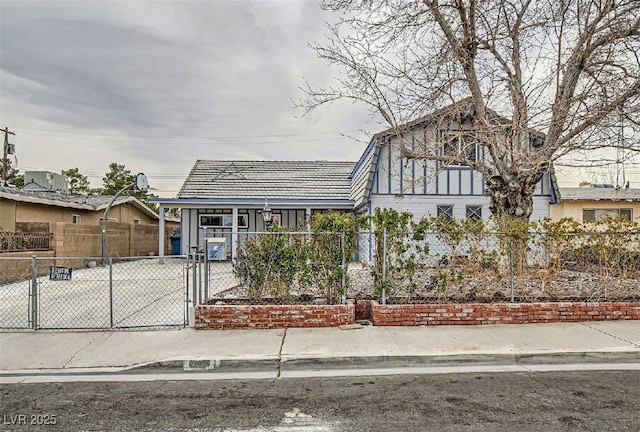 tudor-style house featuring a fenced front yard and a gate