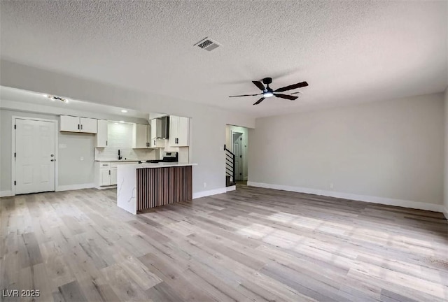 kitchen with light wood finished floors, open floor plan, visible vents, and white cabinetry