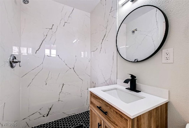 bathroom with a marble finish shower and vanity
