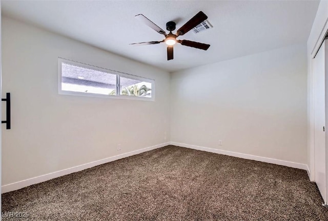 unfurnished room with baseboards, visible vents, a ceiling fan, and dark colored carpet