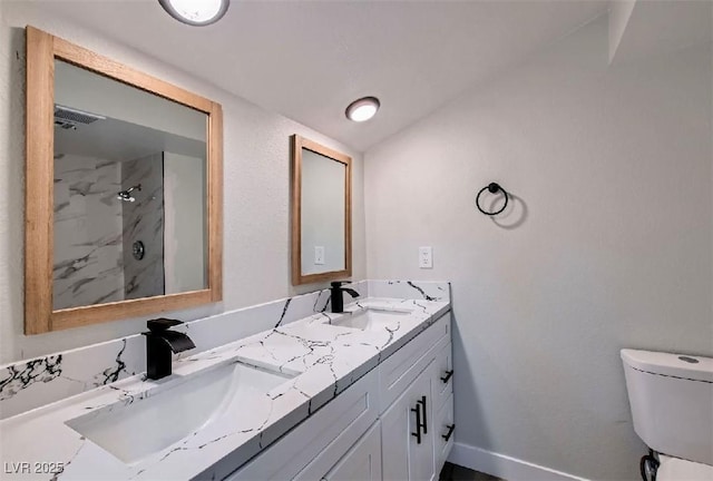 bathroom with a stall shower, double vanity, toilet, and a sink