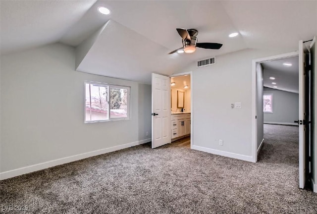 unfurnished bedroom featuring connected bathroom, lofted ceiling, baseboards, visible vents, and carpet
