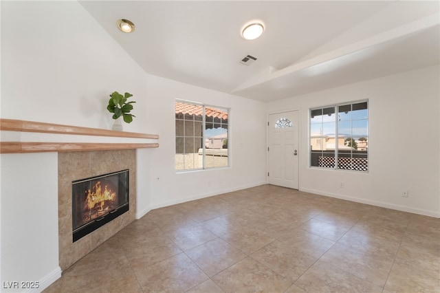 unfurnished living room with lofted ceiling, tile patterned flooring, visible vents, baseboards, and a tiled fireplace