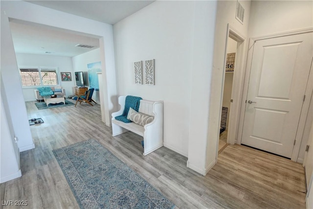 hall featuring wood finished floors, baseboards, and visible vents