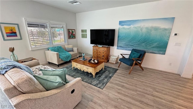 living area featuring baseboards, visible vents, and wood finished floors