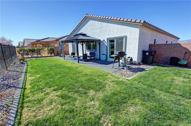 back of property with a patio area, a gazebo, stucco siding, a fenced backyard, and a yard
