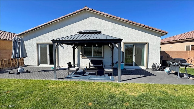 rear view of property featuring stucco siding, a gazebo, and a yard