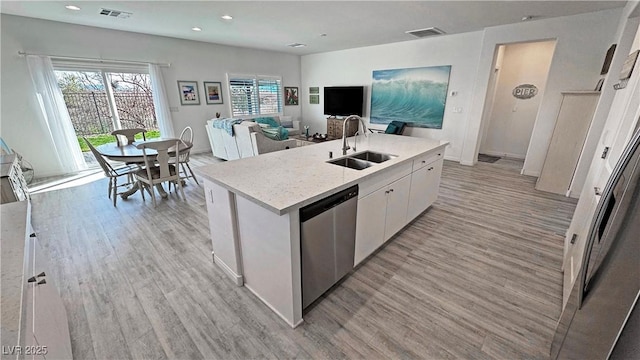 kitchen featuring visible vents, light wood-type flooring, a sink, and dishwasher
