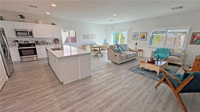 kitchen with open floor plan, a sink, appliances with stainless steel finishes, and visible vents