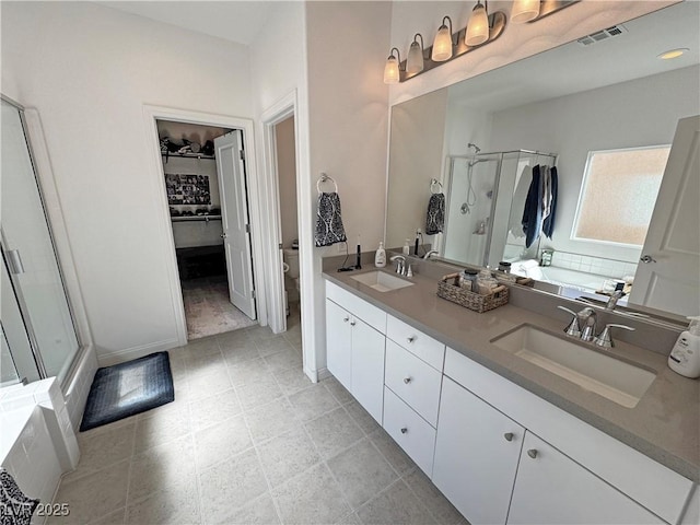 full bath with toilet, a sink, a shower stall, and visible vents