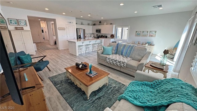 living room with visible vents, recessed lighting, and light wood-type flooring