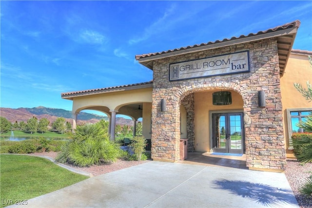 doorway to property featuring french doors, stone siding, stucco siding, and a mountain view