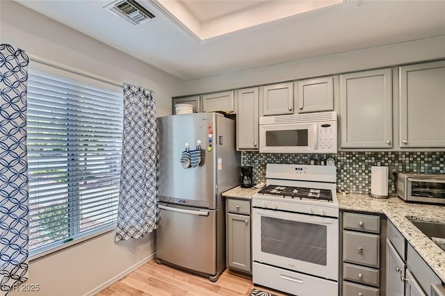 8628 Desert Holly Dr, Las Vegas, NV 89134 - kitchen with light wood-style floors, gray cabinets, visible vents, and white appliances