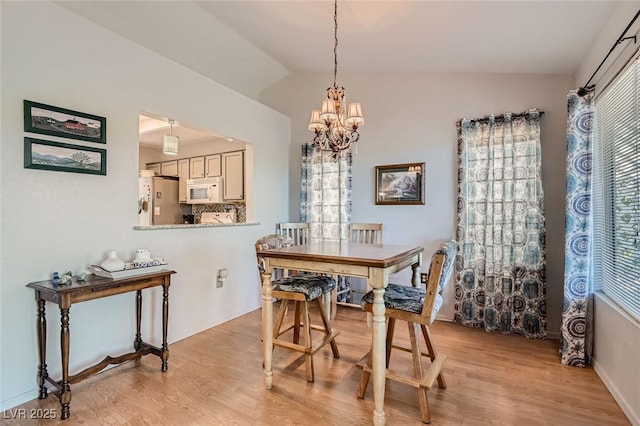 8628 Desert Holly Dr, Las Vegas, NV 89134 - dining area with baseboards, vaulted ceiling, light wood-type flooring, and a notable chandelier