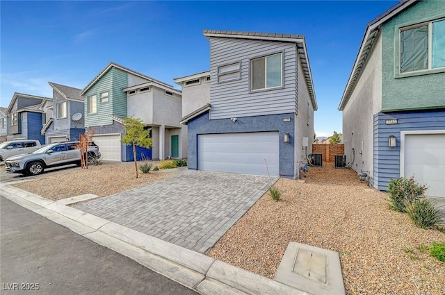 view of front facade with a residential view, stucco siding, driveway, central AC, and a garage