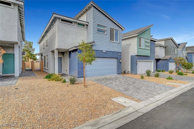 view of front of house featuring fence, decorative driveway, a garage, and stucco siding