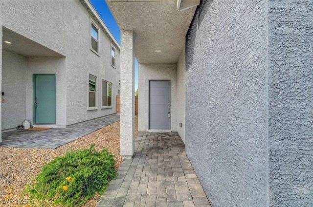 entrance to property with a patio and stucco siding