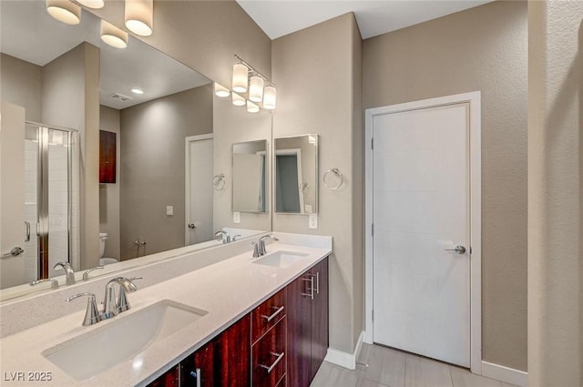 full bathroom with a shower stall, baseboards, a sink, and toilet