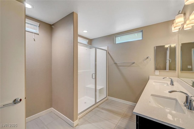 full bath featuring a sink, baseboards, a shower stall, and double vanity