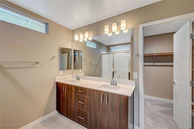 bathroom with a sink, baseboards, and a stall shower