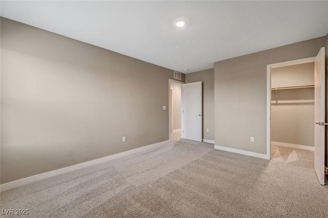 unfurnished bedroom with visible vents, baseboards, a walk in closet, and carpet floors