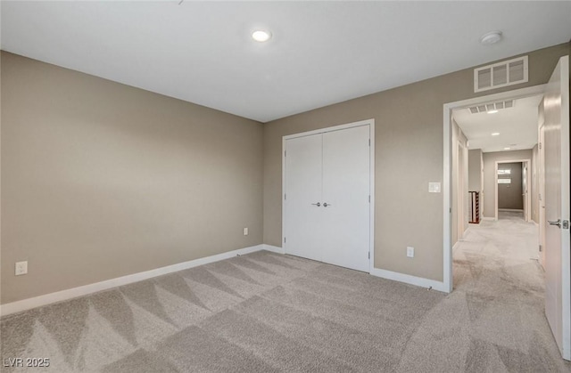 unfurnished bedroom featuring visible vents, light colored carpet, and baseboards