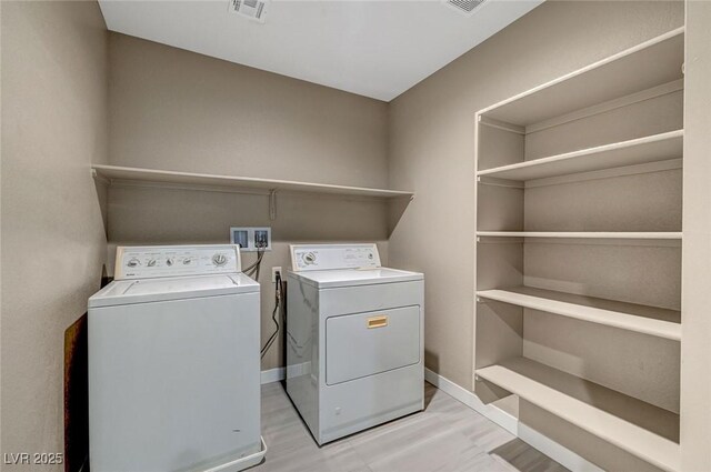 washroom with visible vents, baseboards, washer and dryer, and laundry area