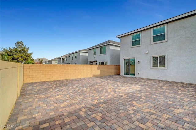 rear view of property with a fenced backyard, a residential view, a patio, and stucco siding