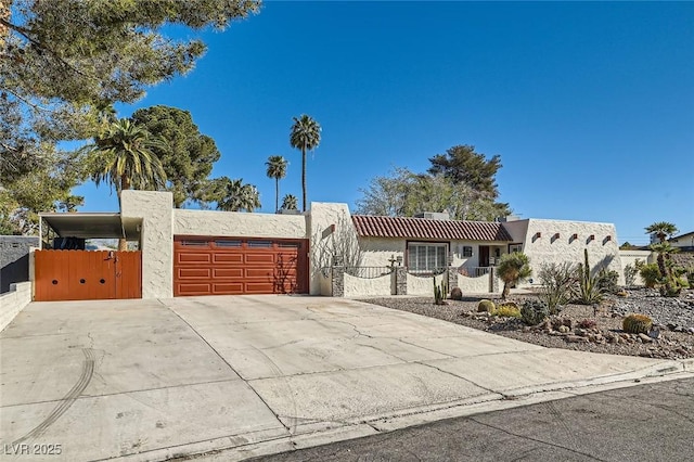 view of front of house with a fenced front yard, a gate, driveway, an attached garage, and stucco siding