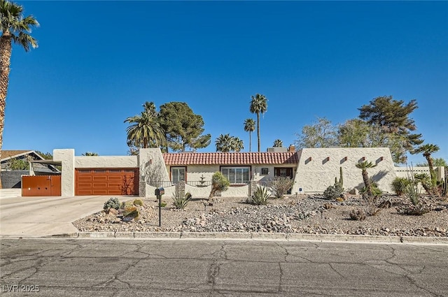 view of front of home with a garage, driveway, fence, and stucco siding