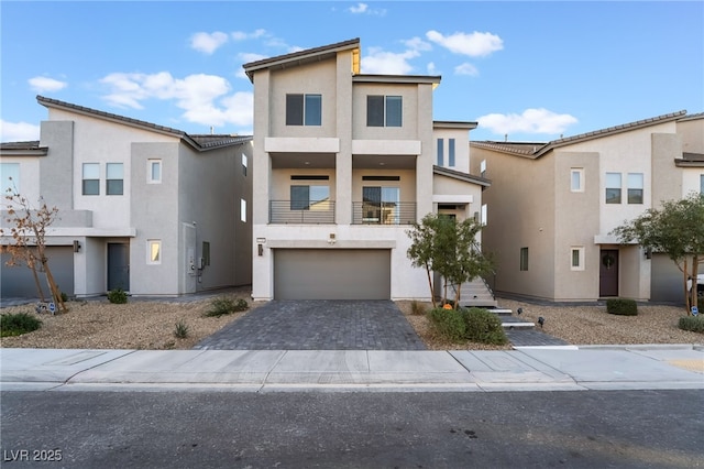 view of front of house featuring stucco siding, a garage, and decorative driveway
