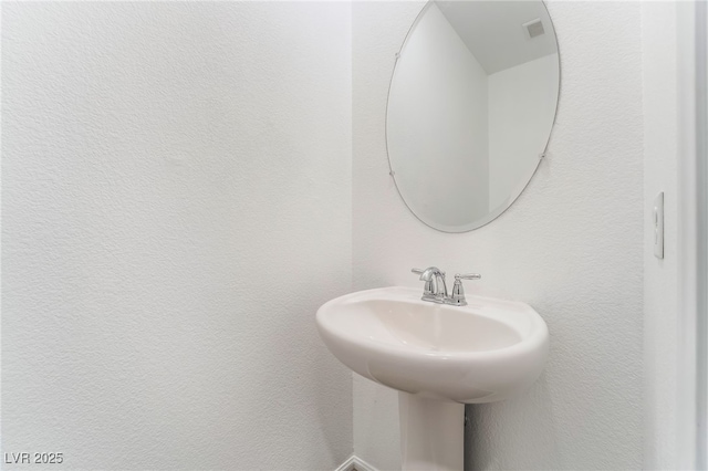bathroom with a sink, a textured wall, and visible vents