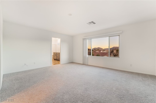 spare room featuring light colored carpet and visible vents
