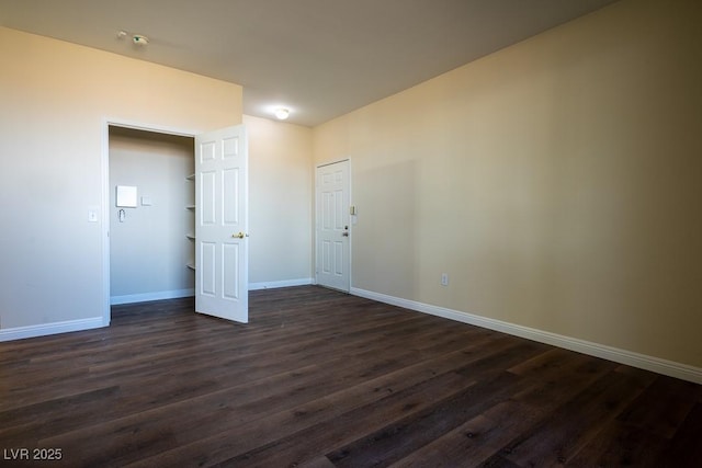 spare room featuring dark wood-style flooring and baseboards
